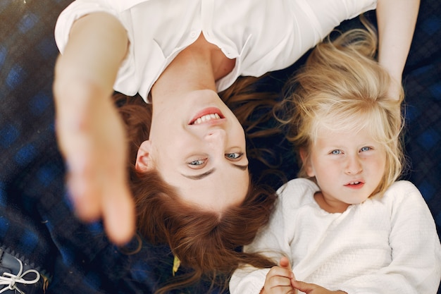 Free photo mother with little daughter lying on a plaid in a summer park