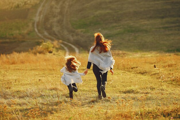 Mother with little daughter playing in a autumn field