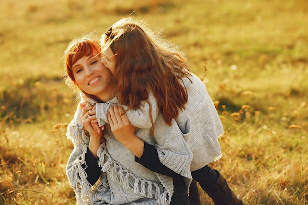 Мать с маленькой дочерью, играющей в осеннем поле