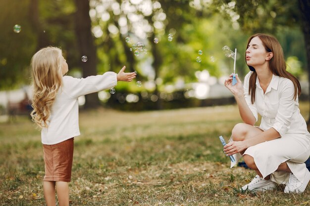 夏の公園で遊ぶ幼い娘を持つ母