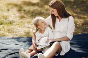 Foto gratuita madre con figlia piccola seduta su un plaid e leggere il libro