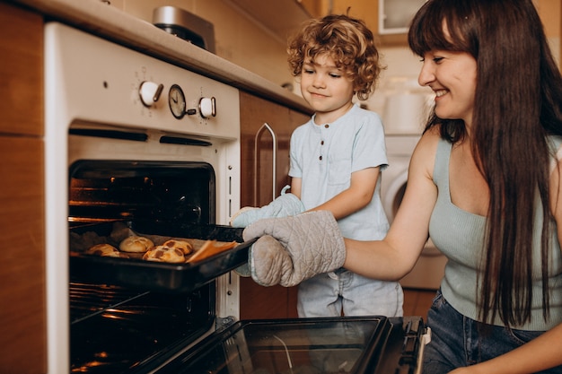 Foto gratuita madre con i biscotti di cottura del piccolo figlio nel forno