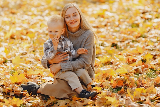 Мать с маленьким сыном сидит в осеннем поле