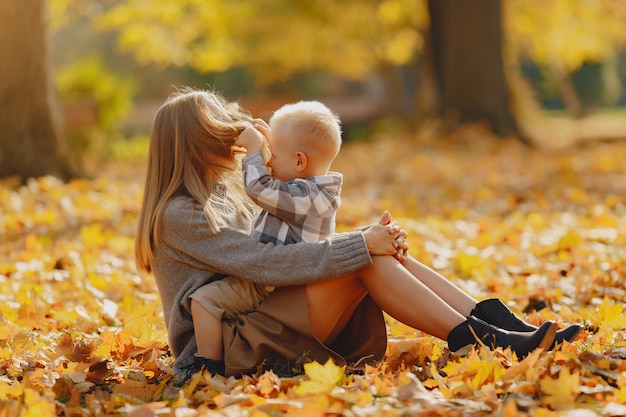 Мать с маленьким сыном сидит в осеннем поле