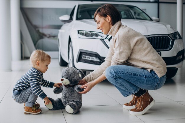 Mother with son in a car showroom playing with teddy bear