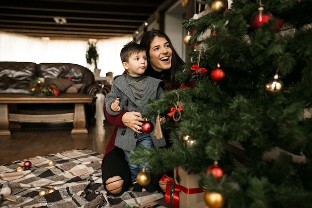 Mother with son on Christmas by the fir-tree