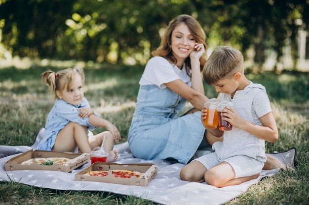 Mother with son and daughter eating pizza in park