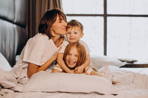 Mother with son and daughter having fun in bed