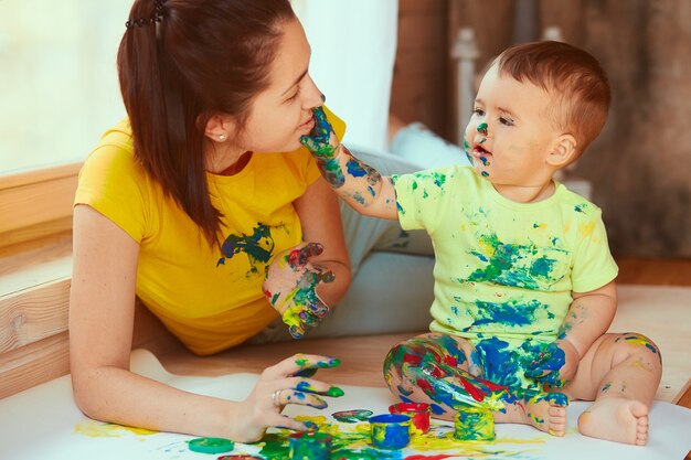 The mother with son painting a big paper with their hands