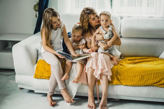 Бесплатное фото Мама с тремя детьми читает книгу в домашней обстановке