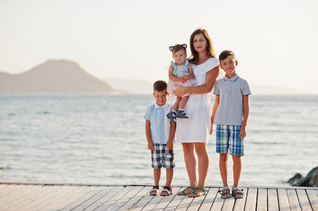 Mother with three kids at Turkey resort against Mediterranean sea stand on the pier