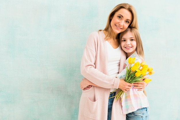 Мать с тюльпанами и дочь обнимаются