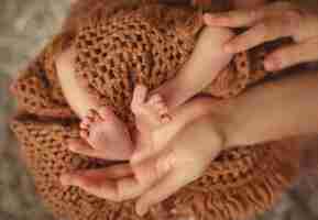 Бесплатное фото Матери руки держат милые и маленькие ноги новорожденного ребенка