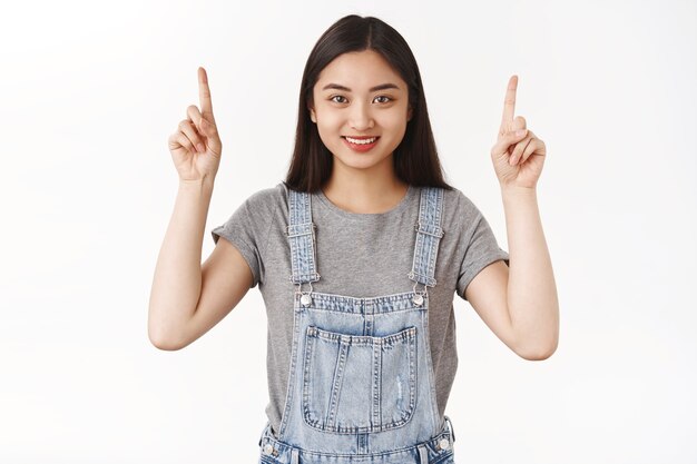 Motivated good-looking confident pleasant happy smiling asian brunette girl aim only forward straight top success pointing up index fingers grin camera delighted propose cool offer promo