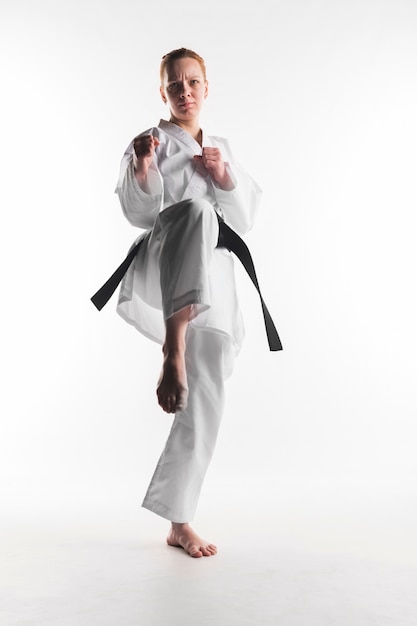 Free photo motivated karate woman kicking front view