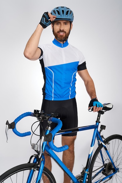 Motivated male cyclist smiling at camera while posing indoors portrait of happy bearded rider with