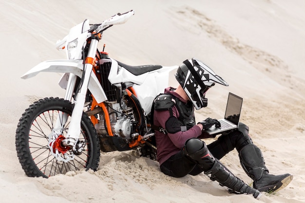 バイクライダーが砂漠でラップトップを閲覧