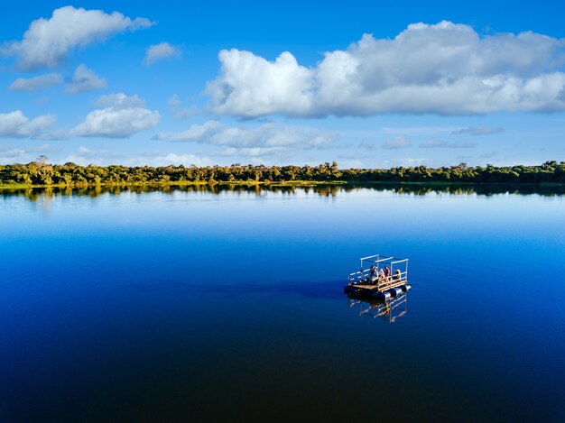 Motorboat in the lake surrounded by beautiful green trees under a cloudy sky