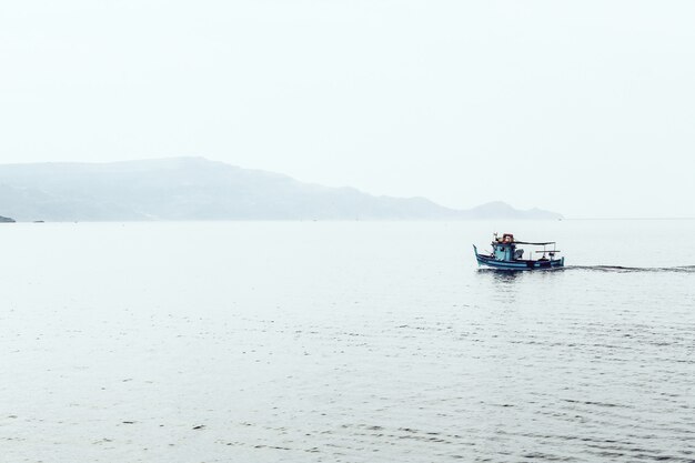 Motorboat on the sea surrounded by mountains enveloped in fog
