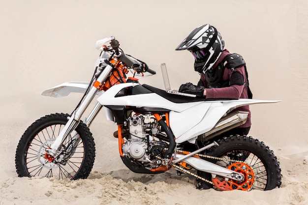 Мотоциклист просматривает ноутбук в пустыне