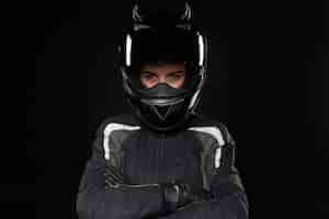 Бесплатное фото Мотоциклетный спорт, экстрим, соревнования и адреналин. активная молодая гонщица в защитном шлеме и форме собирается участвовать в шоссейных гонках или мотокроссе, скрестив руки на груди