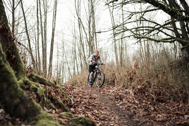 Mountain biker riding the bike on forest trail in autumn