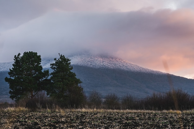 Foto gratuita montagna ricoperta di neve e un cielo nuvoloso durante il tramonto