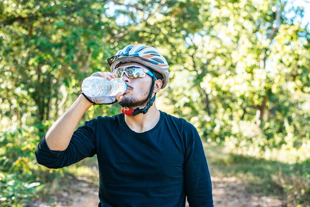 Mountain cyclists stand on the top of the mountain and drink a bottle of water.