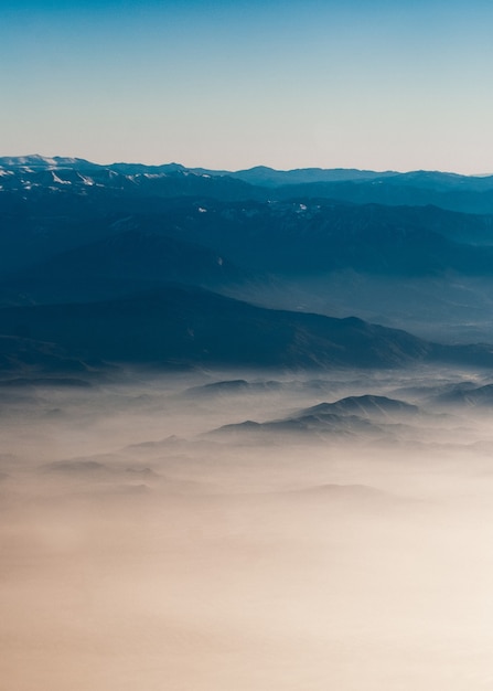 Catena montuosa con sagome visibili attraverso la nebbia colorata del mattino