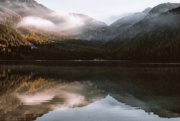 Mountain Reflection on Body of Water Under White Sky at