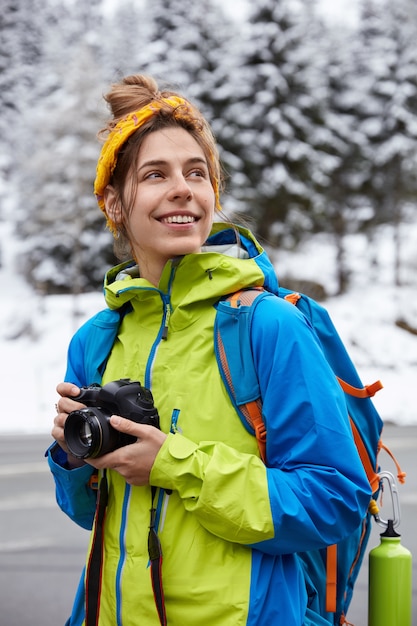 Free photo mountain trek and adventure concept. happy dreamy female climber enjoys beautiful landscape
