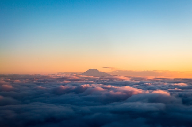 昼間の白い雲の上の山