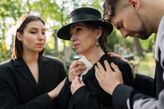 Mourning family dressed in black crying at a grave in the cemetery