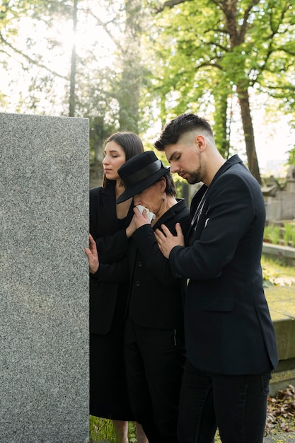 Free photo mourning family dressed in black crying at a grave in the cemetery