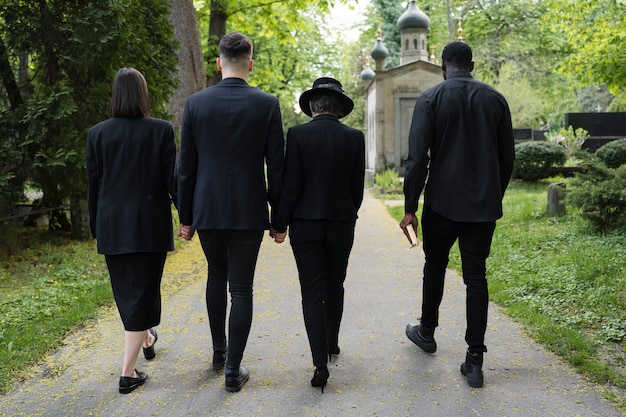 Free photo mourning family with priest in the cemetery