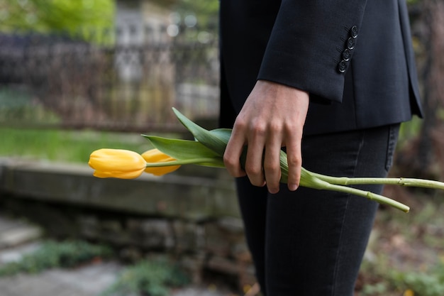 Free photo mourning man bringing tulips at the cemetery