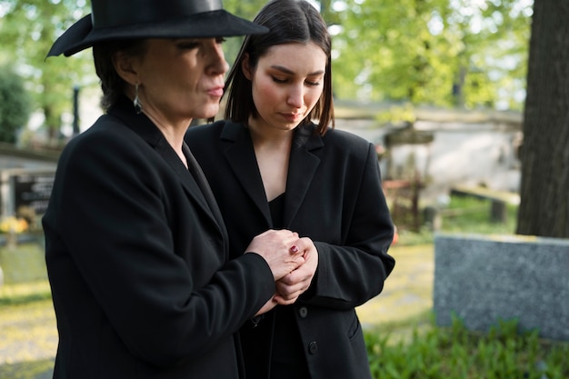Mourning mother and daughter at a grave in the cemetery
