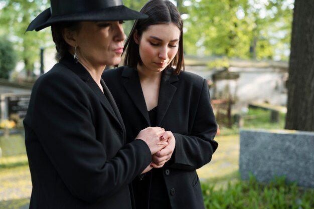 Скорбящие мать и дочь у могилы на кладбище