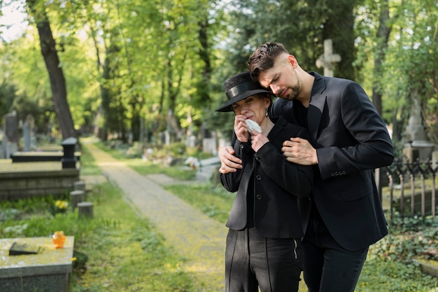 Donna in lutto al cimitero consolata dall'uomo