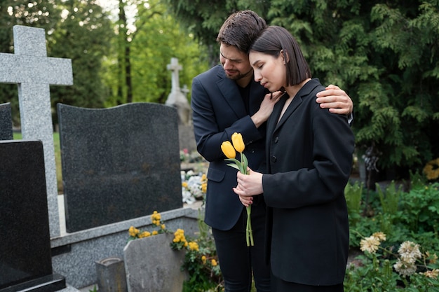 묘지에서 애도하는 여자가 남자에게 위로를 받고 있다