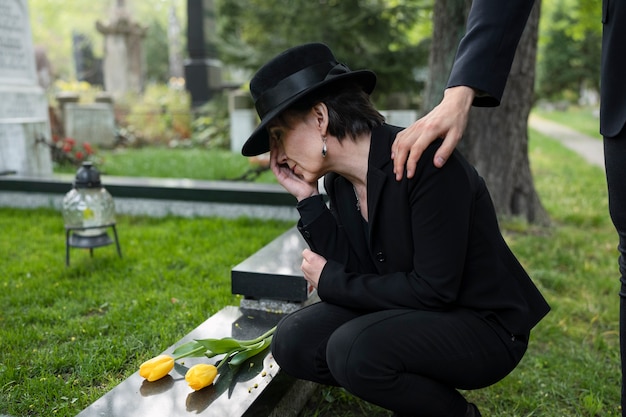 男に慰められている墓地で喪に服している女性