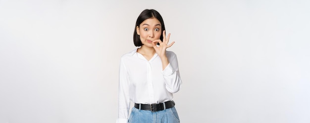 Mouth shut Young asian woman seal lips showing taboo dont speak keep quiet sign hiding secret standing over white background