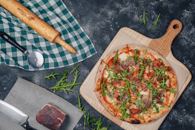 Mouth-watering Neapolitan pizza on a blackboard with various ingredients, free space for text