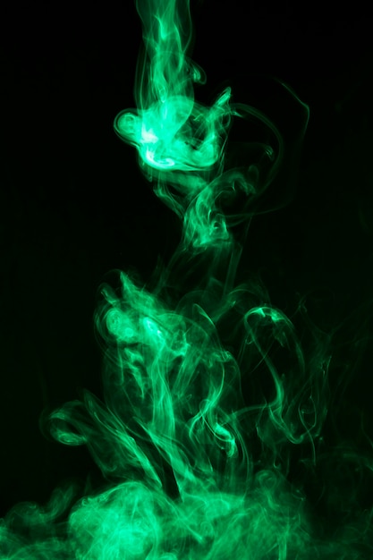 黒の背景に明るい緑の煙の動き