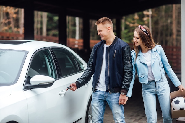 新しいビルドに移動し、カップルは白い車の近くの新しい家にドライブします。