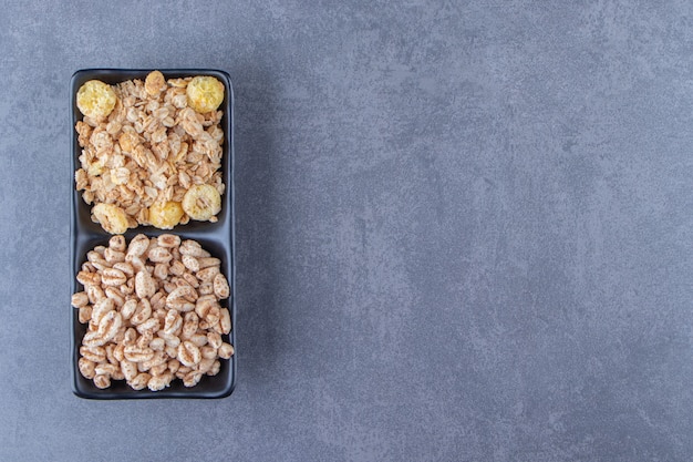 Muesli and cornflakes in bowls, on the marble background. High quality photo