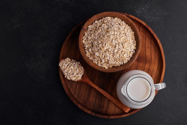 Mueslies in wooden cups with a jar of milk in a wooden plate. 