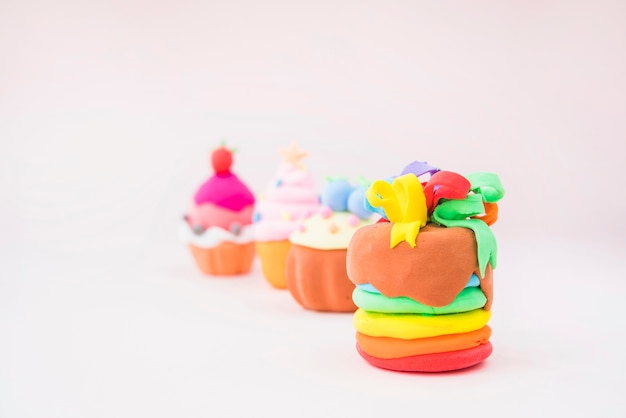 Muffins made with colorful clay on pink background