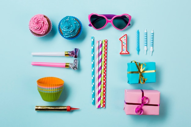 Кексы; солнцезащитные очки; воздуходувки для вечеринок; соломинки для питья; свечи и подарочные коробки; бенгальский огонь на синем фоне