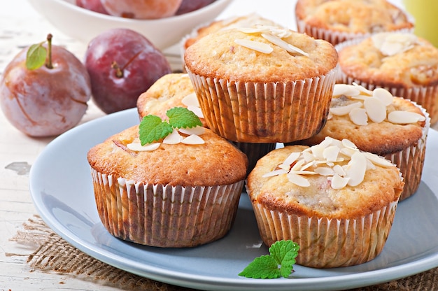 Muffins with plums and almond petals decorated with mint leaves